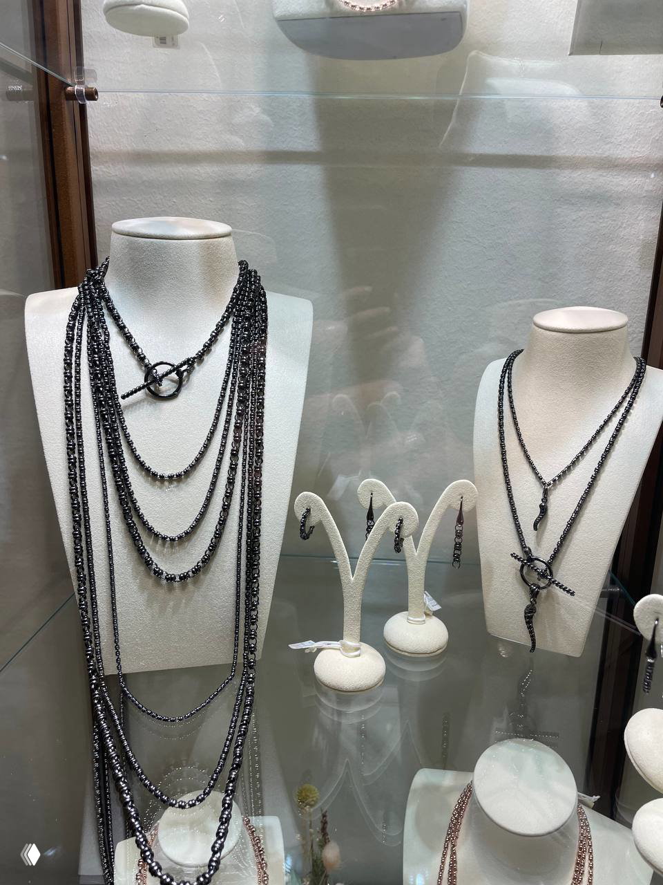 Витрина с несколькими многослойными и однотонными колье, серьгами и аксессуарами — ассортимент украшений в магазине во Флоренции.