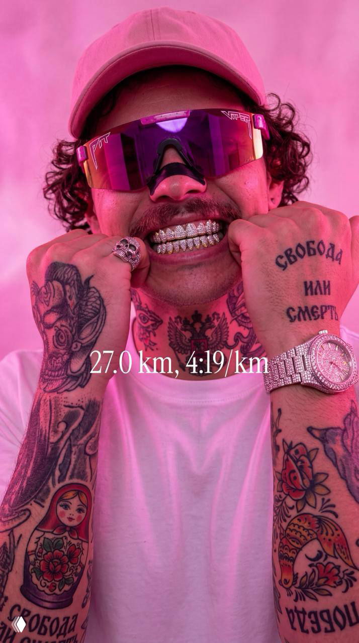 Крупный план мужчины в розовой кепке и зеркальных очках, он показывает зубы с украшением, фон подсвечен розовым — модный, насыщенный портретный кадр.