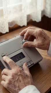 Руки пожилого человека, нажимающие кнопки на кассете или плеере — ностальгический AI‑образ с текстурой и тёплой гаммой.