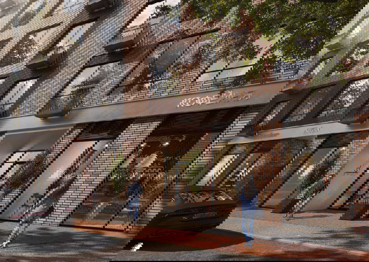 Входная группа и коммерческие помещения на первом этаже новостройки: стеклянные витрины, вывески, люди у входа и припаркованный автомобиль.