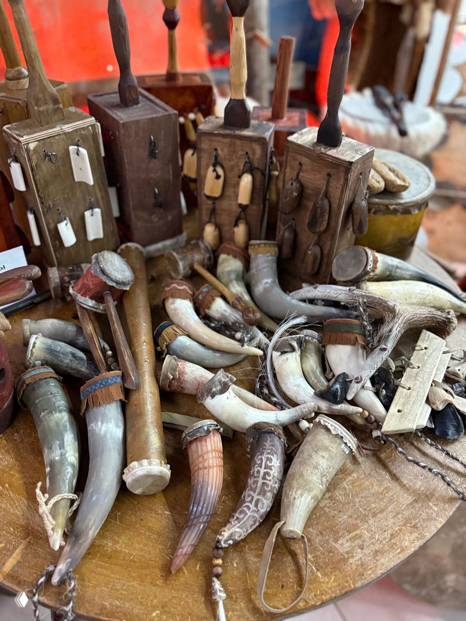 Стол с народными ремесленными изделиями: рога, деревянные кивки и музыкальные атрибуты, сувениры коренных народов Якутии на ярмарке.