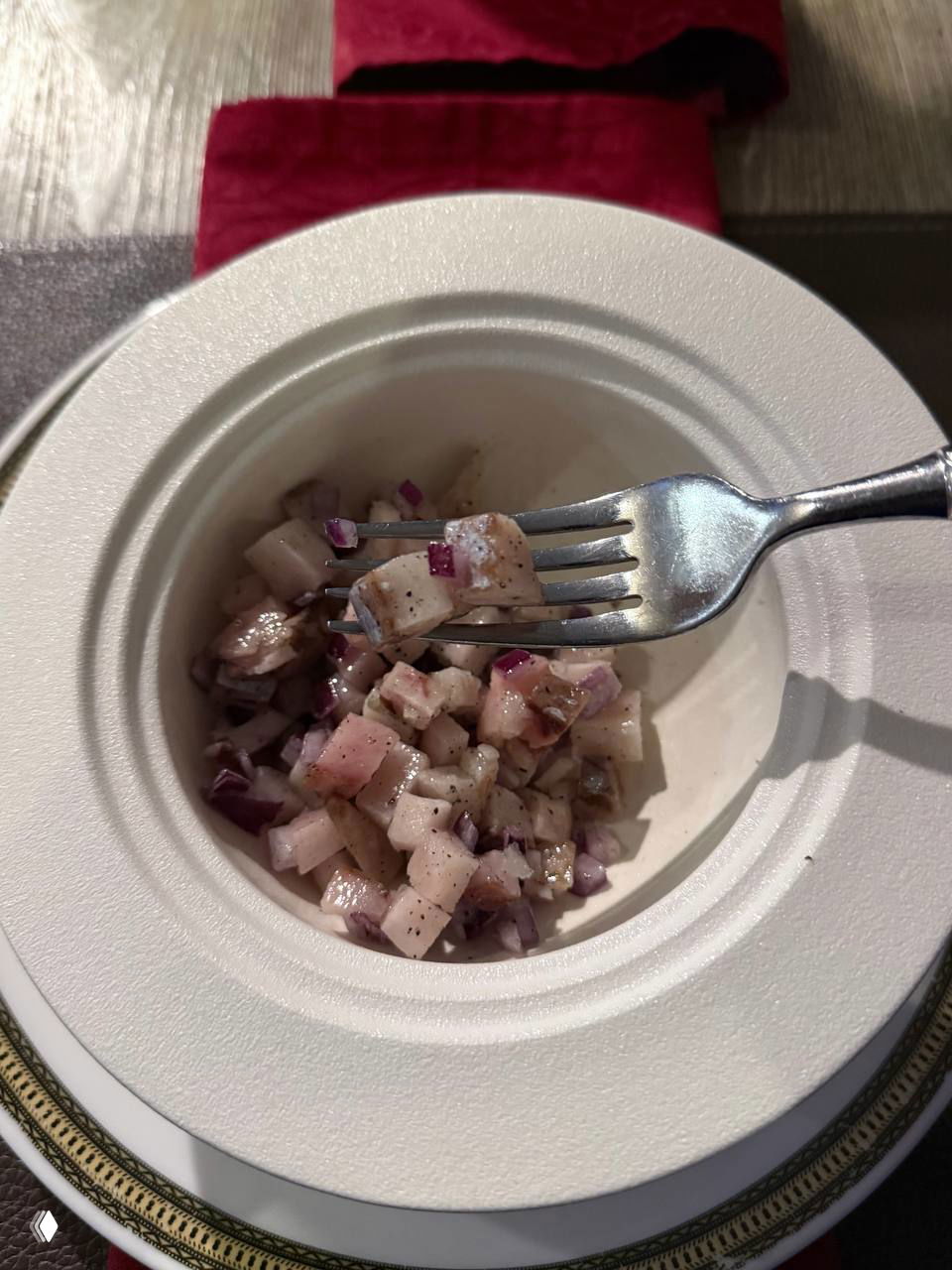 Порция индигирки — салата из замороженной рыбы — в белой тарелке с вилкой, видна нарезанная рыба и лук, северная кухня на дегустации автора.