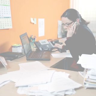 Женщина в офисе за рабочим столом: говорит по телефону, ноутбук и стопки документов, иллюстрация инспекции рабочего места.