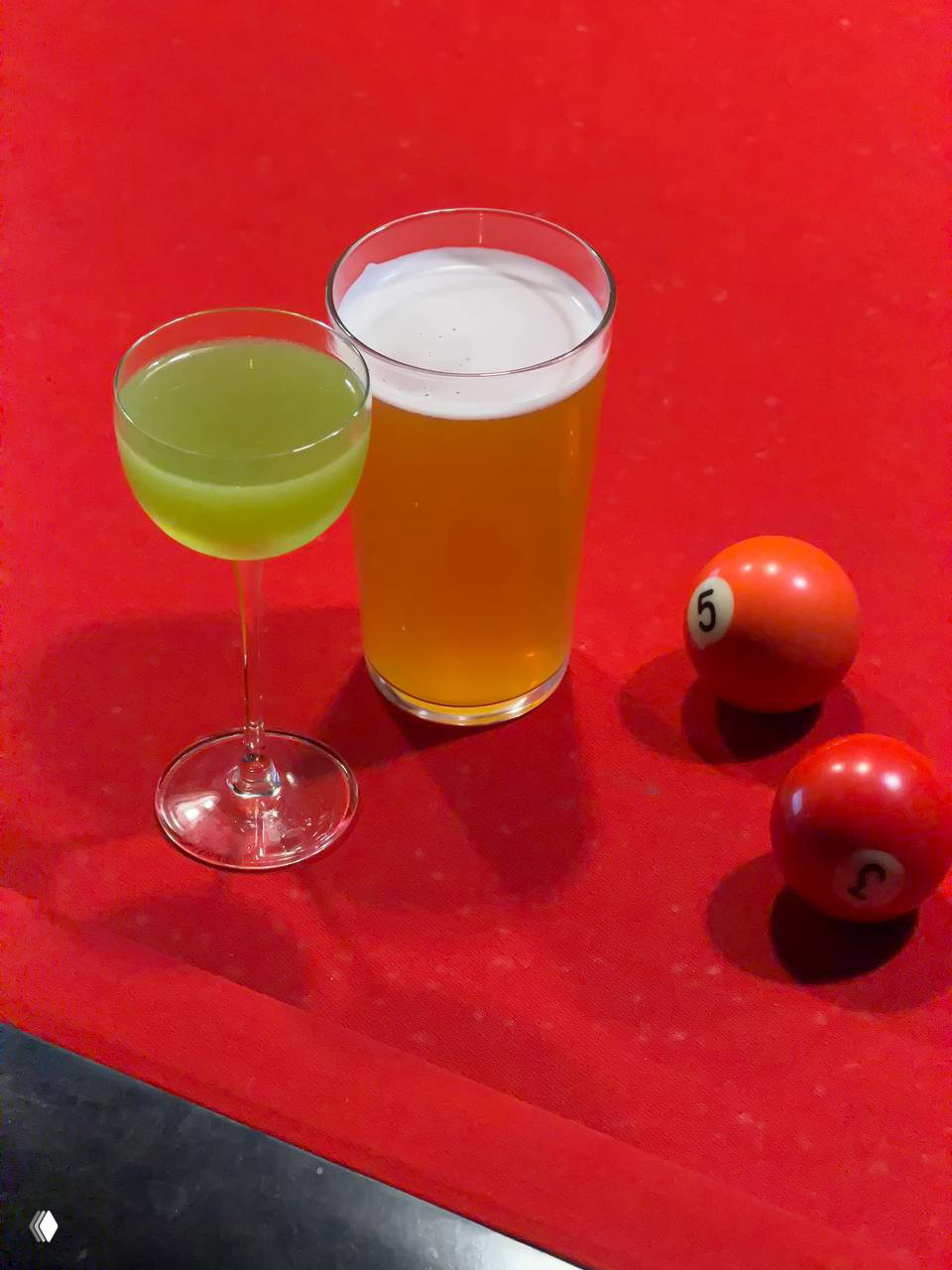Коктейль Киви и пинта пива на красном бильярдном сукне рядом с шарами — сочетание напитков и развлечений в пространстве OSSU