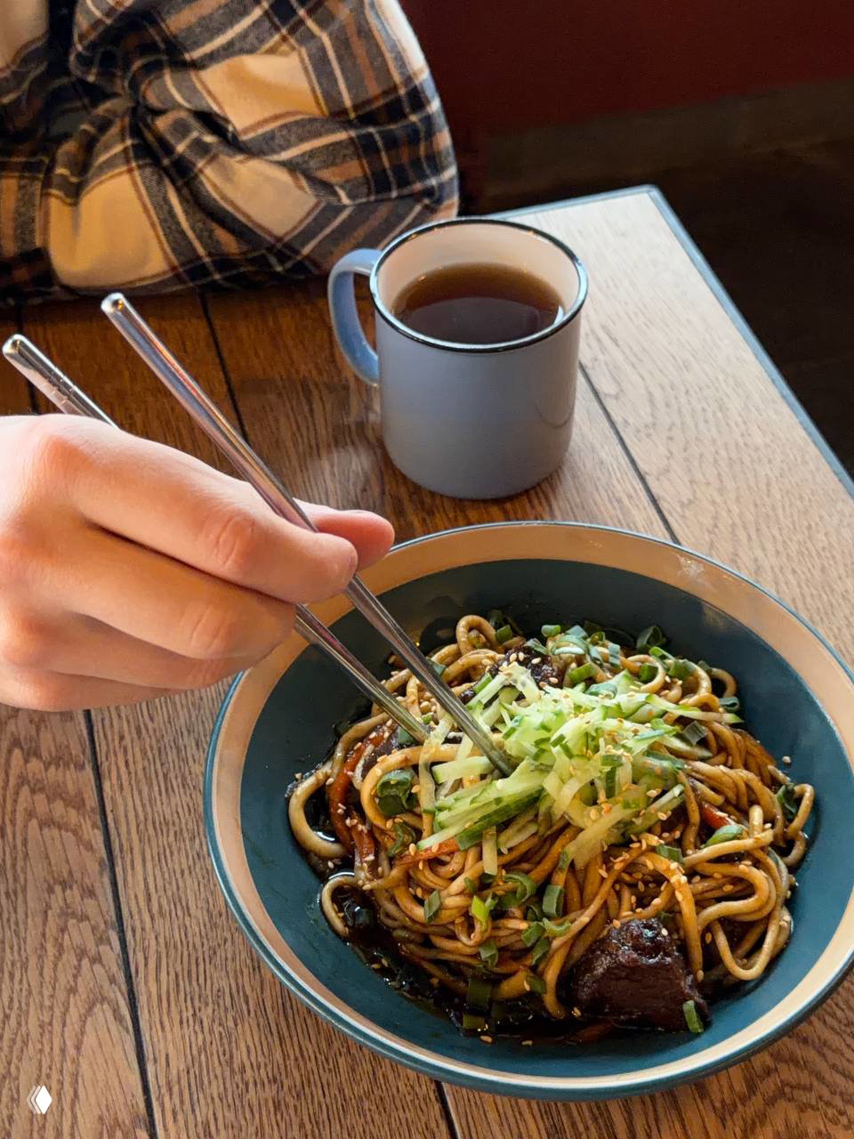 Ручная китайская лапша с говяжьими щеками в соусе чёрные бобы: миска с палочками, зеленью и насыщенным тёмным соусом на деревянном столе