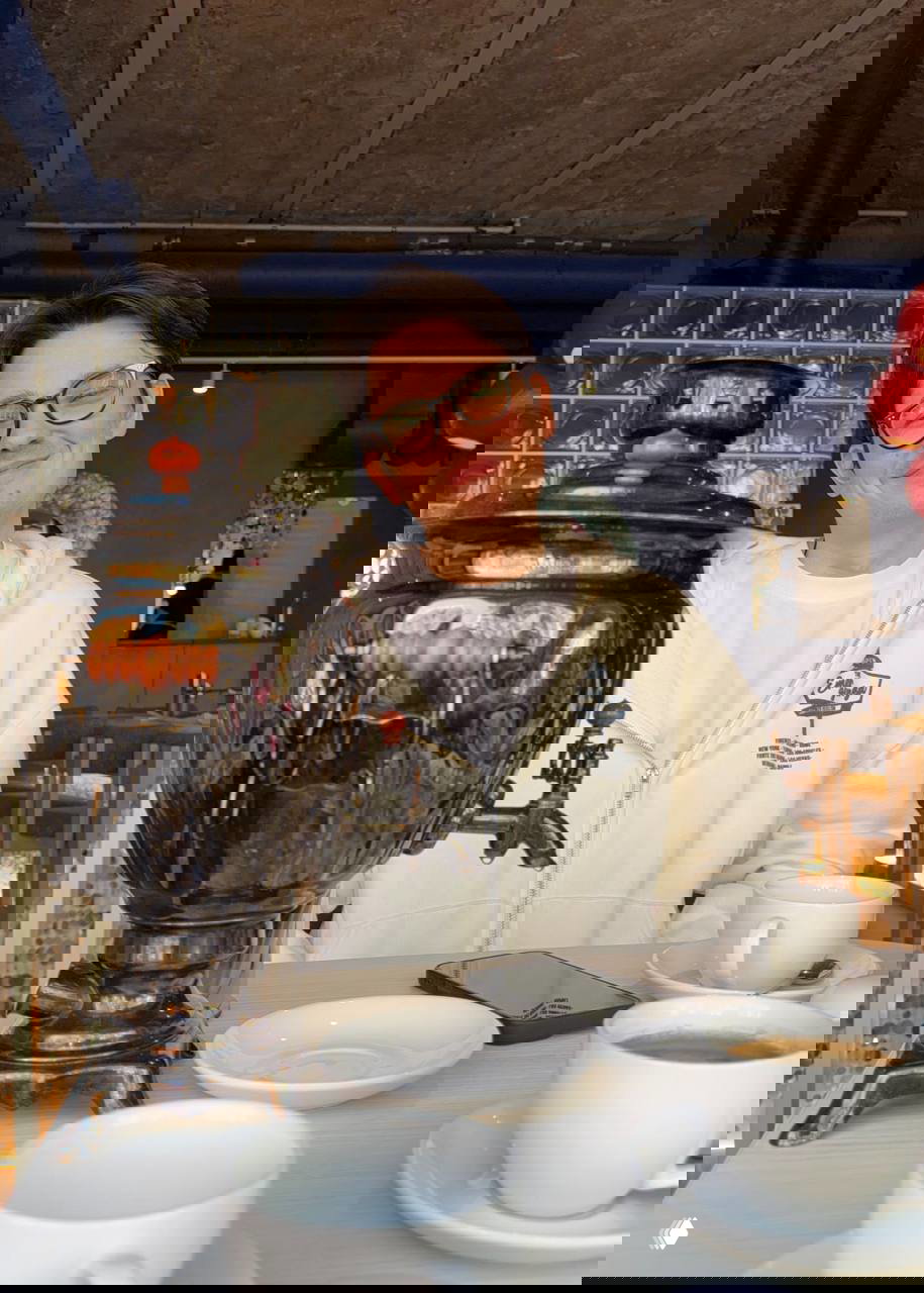 Гость кафе сидит за столом рядом с большим самоваром и чашками — спокойная утренняя сцена дегустации завтрака в Вихри.