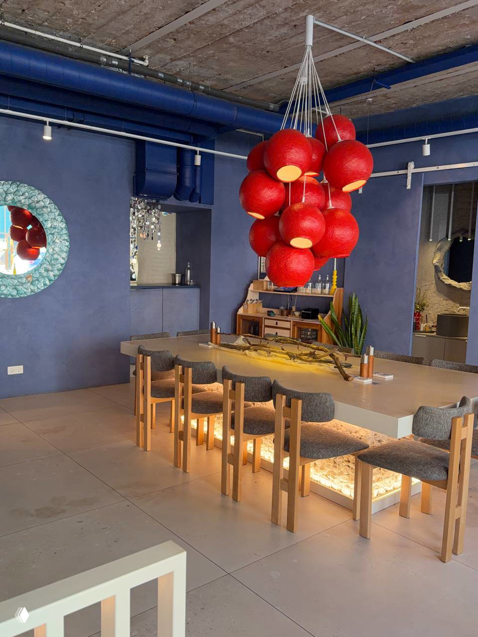 Гардеробная зона кафе: вешалки с зимними пуховиками, растения и витрина с бутылками — уютная и продуманная зона для гостей.