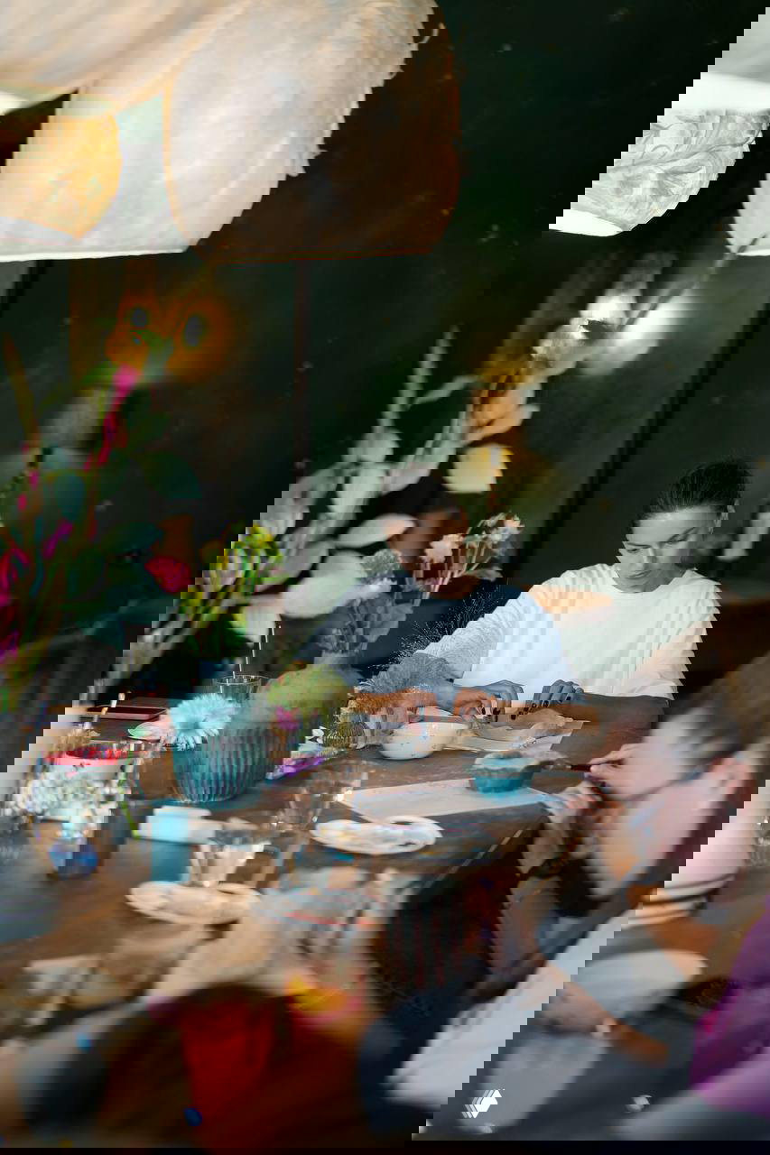 Участницы мастер-класса за длинным столом: рукоделие и керамика, рабочие материалы, декоративные элементы и цветы на столе.