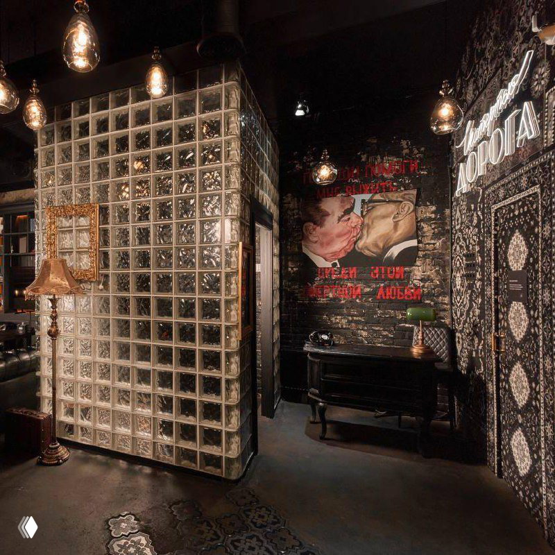 Вид внутри Tangiers Lounge: стеклоблоки, декоративная лампа и настенное граффити с советской эстетикой, сочетание винтажных деталей и современного света.