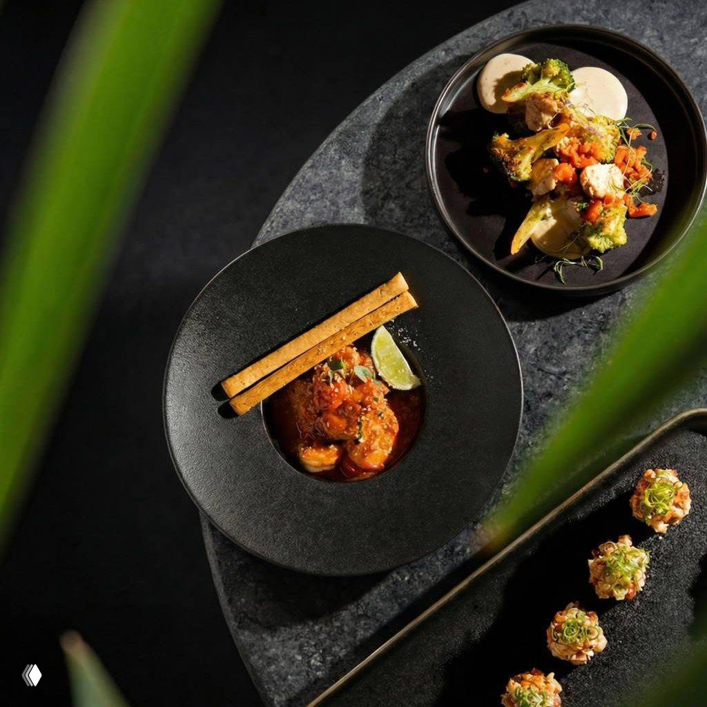 Крупный план блюд в Tangiers Lounge: несколько художественно оформленных тарелок и закусок на темной сервировке, макро-кадр еды в ресторанной подаче.