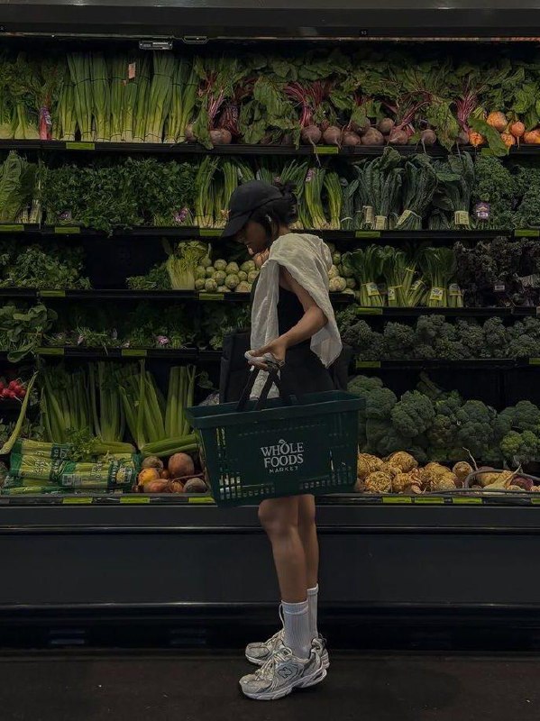 Покупатель с корзиной Whole Foods выбирает свежие зелёные овощи в отделе супермаркета — кадр о закупках для здорового питания.