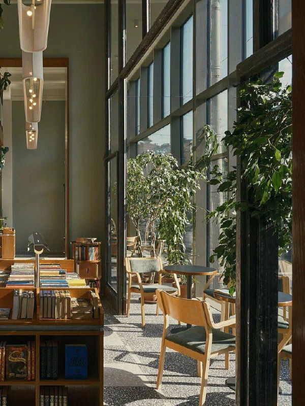 Книжный уголок-кофейня: стеллажи с книгами, столики у окна и мягкие кресла — пространство, где удобно читать и работать с ноутбуком.