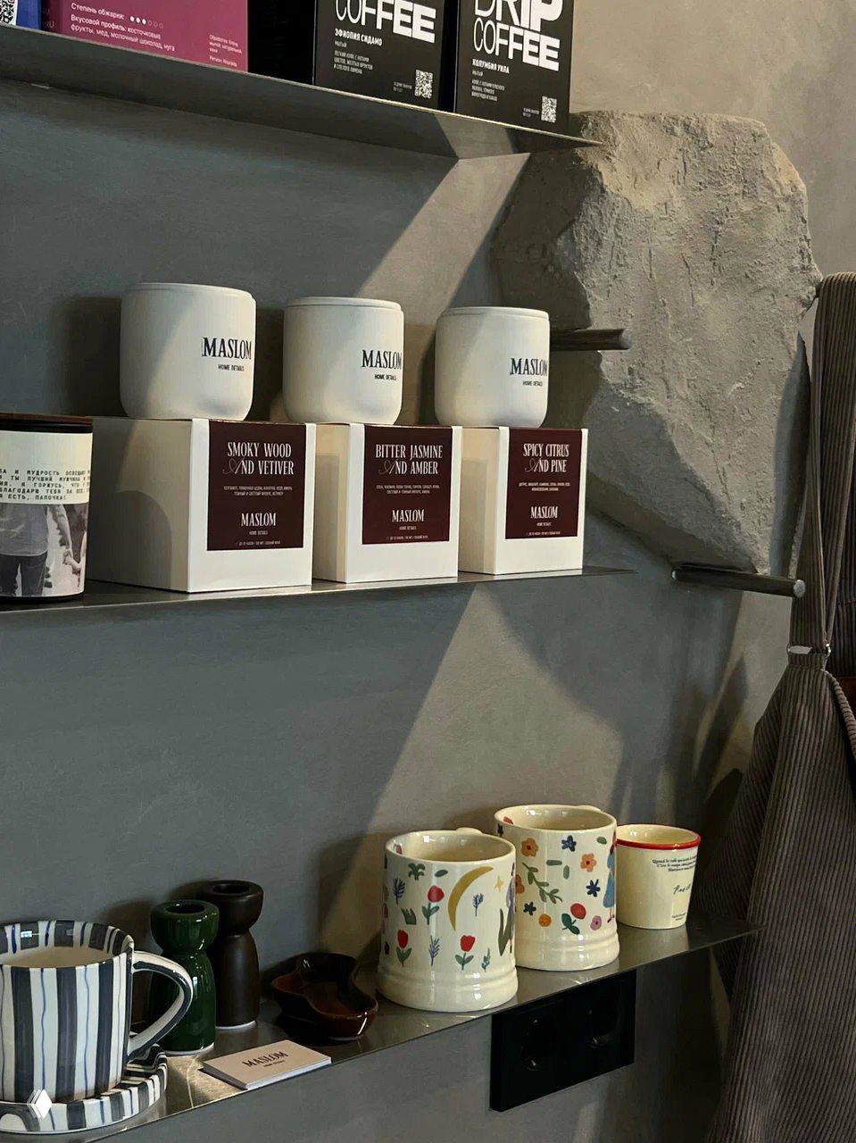 Полки с банковскими баночками и керамическими кружками в кофейне Keny; детали интерьера в нейтральной серо-коричневой палитре.