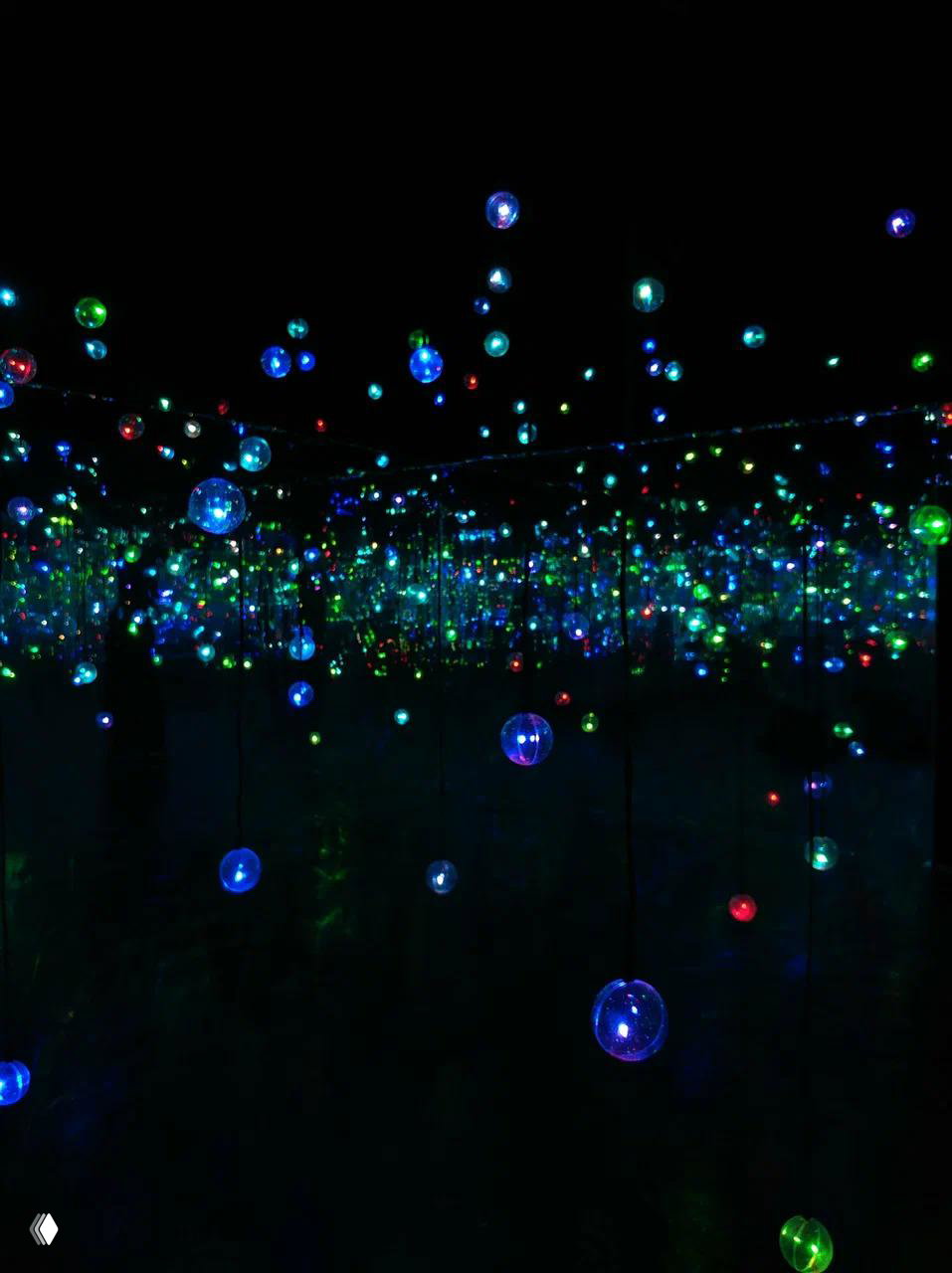 Подвесные сферические светильники на фоне зеркал создают ощущение бесконечного пространства из множества мелких разноцветных огоньков.