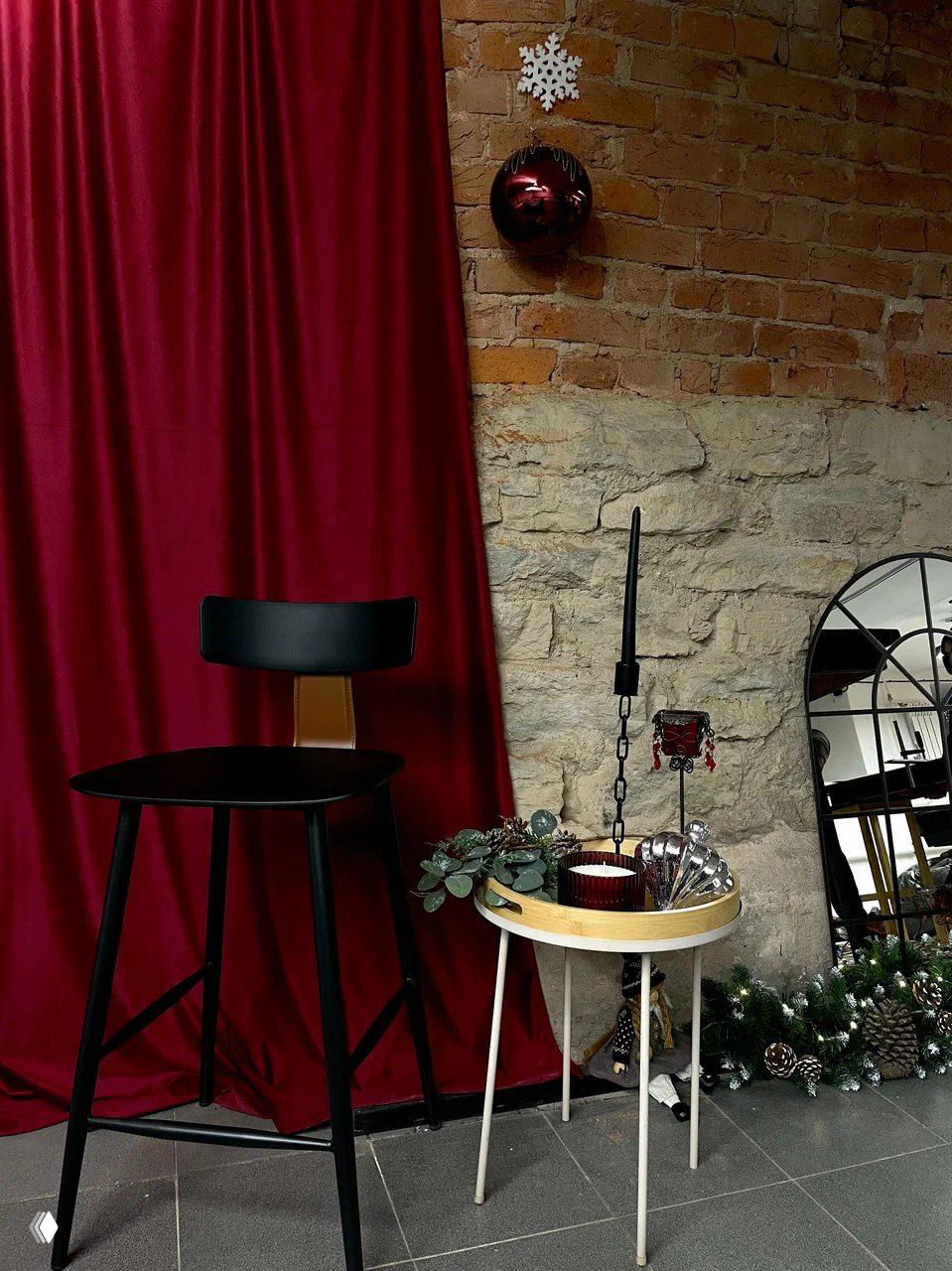 Уютный декоративный угол с красной бархатной шторой, стулом и небольшим столиком — зона для отдыха внутри клуба между партиями