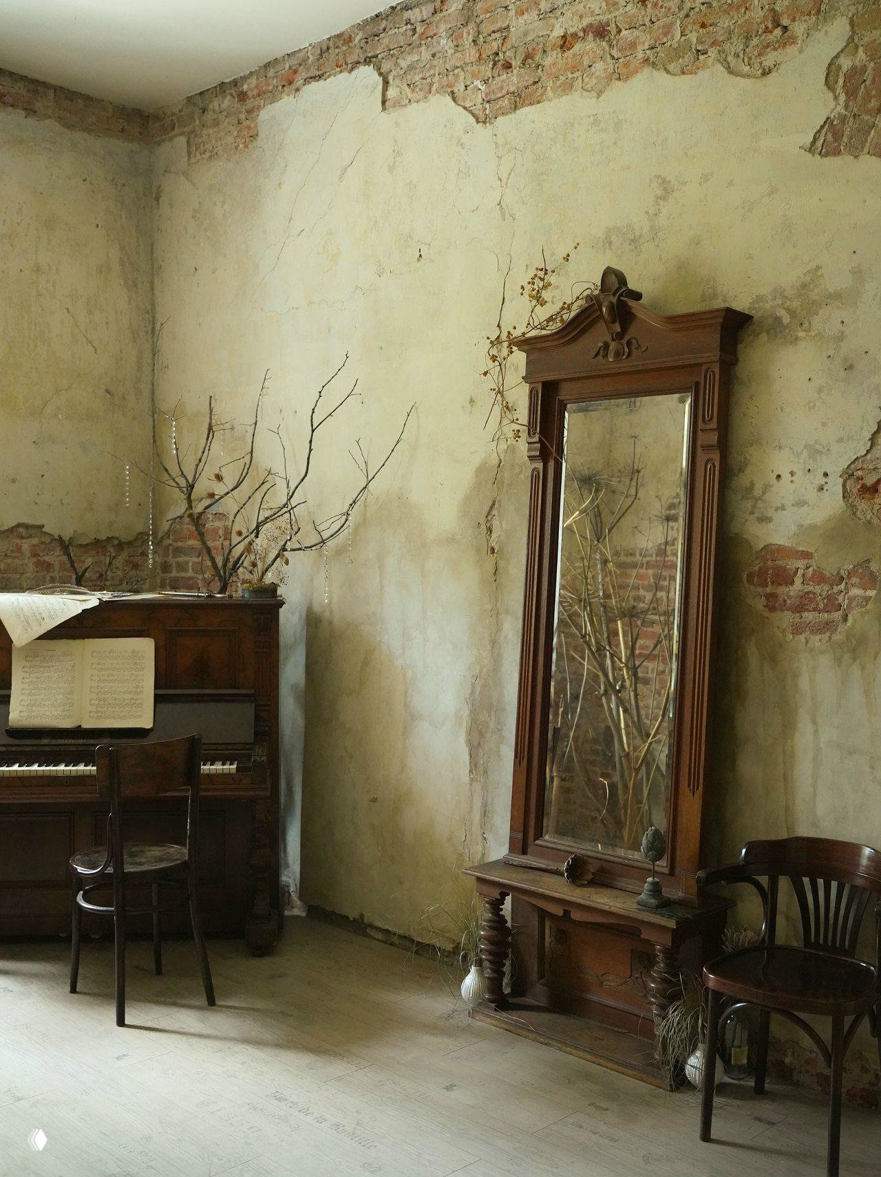 Пианино и высокий резной шкаф-зеркало на фоне потрескавшейся штукатурки — интерьерный кадр с атмосферой старой виллы.