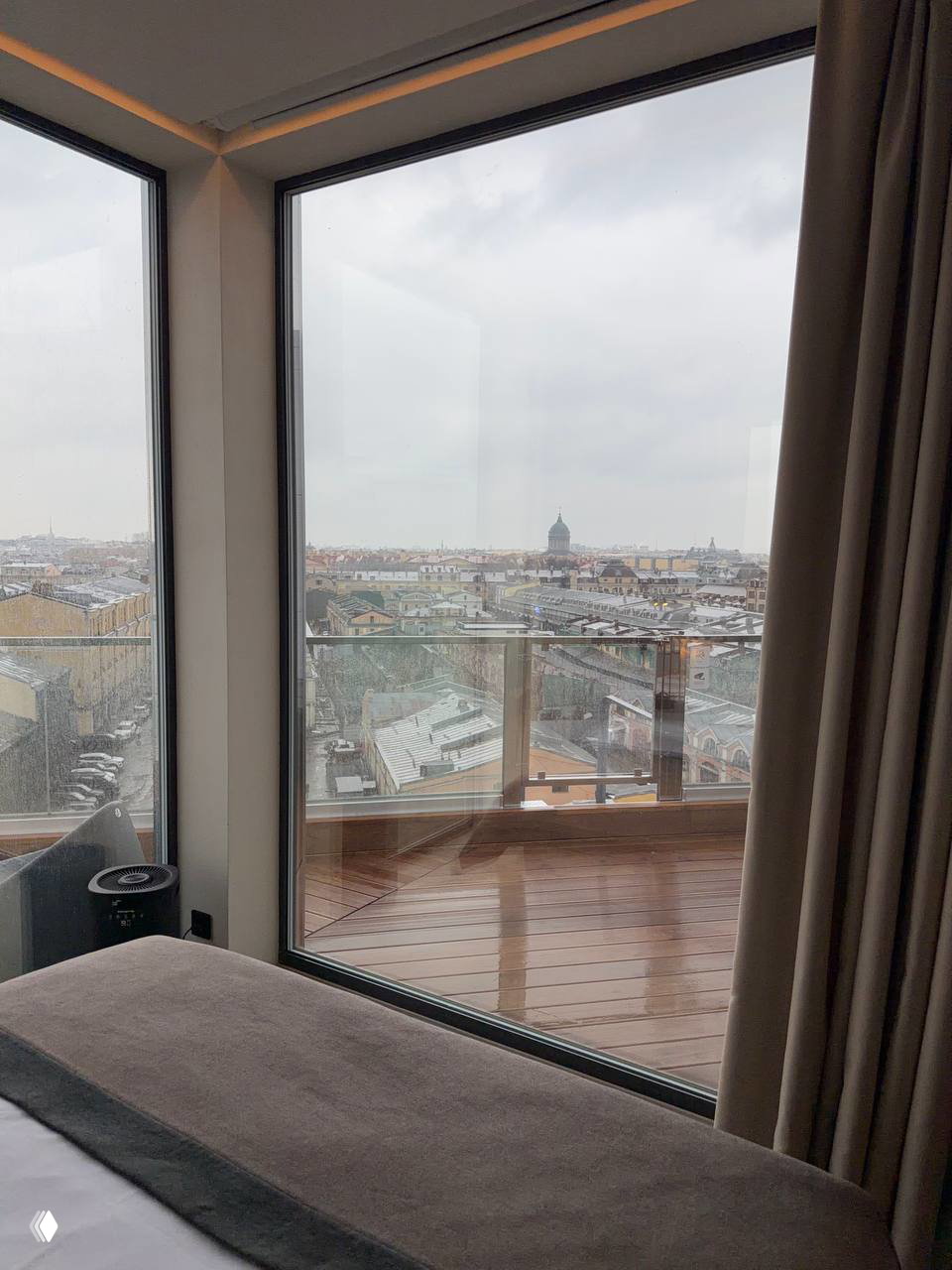 Панорамный вид из окна на исторический центр Петербурга и крыши домов; остеклённая терраса и городская перспектива за стеклом.