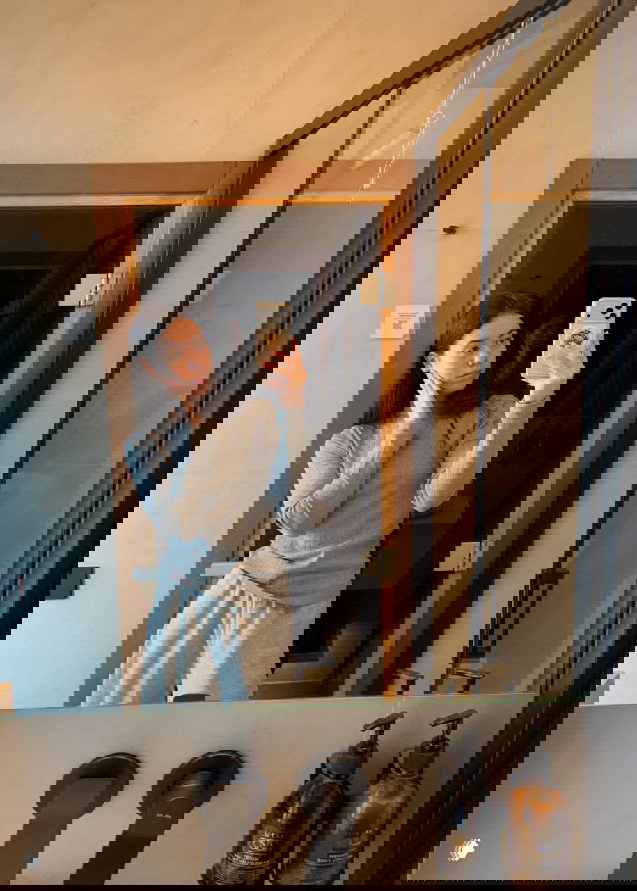 Зеркальная стена возле кровати и потолочный проектор в центре: современный интерьер с тёплым освещением и деревянными поверхностями.