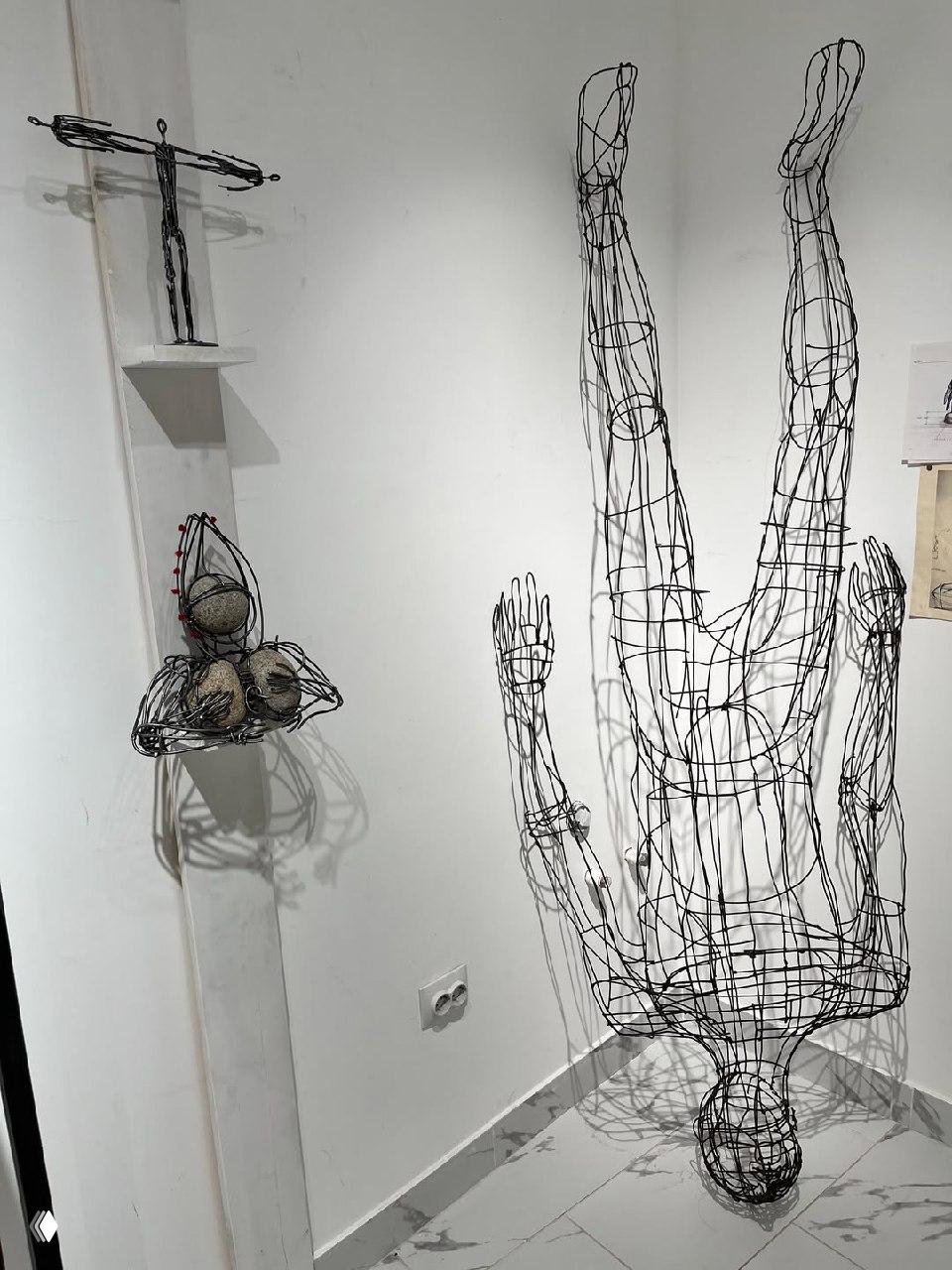 Угловой фрагмент выставки: проволочная полноразмерная фигура человека, рядом проволочные и плетёные мелкие объекты.