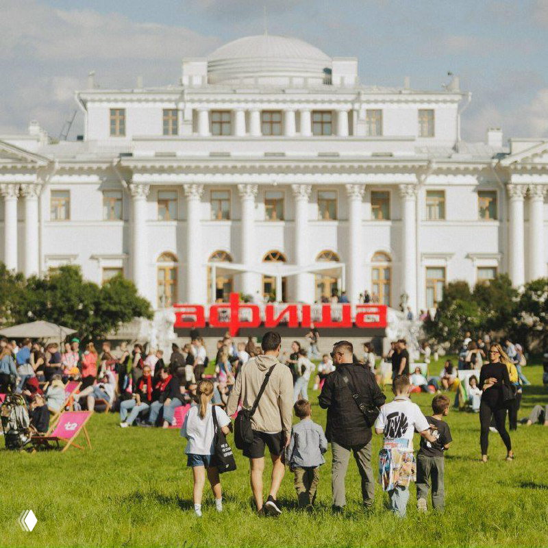 Толпы людей и семьи на газоне у дворца на Елагином острове, на фоне большой красной вывески «афиша» — летняя открытая площадка фестиваля