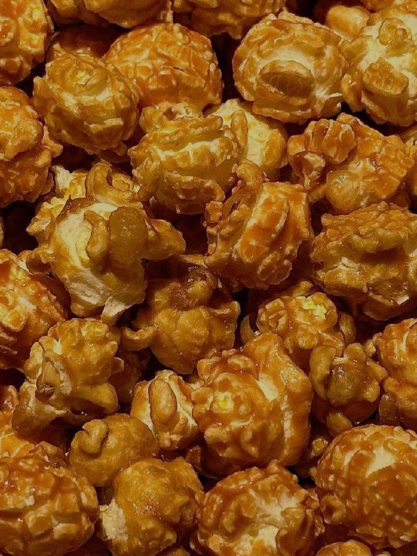 Крупный план карамельного попкорна крупными кусками — аппетитная порция попкорна, которую обещают выдать в акции.