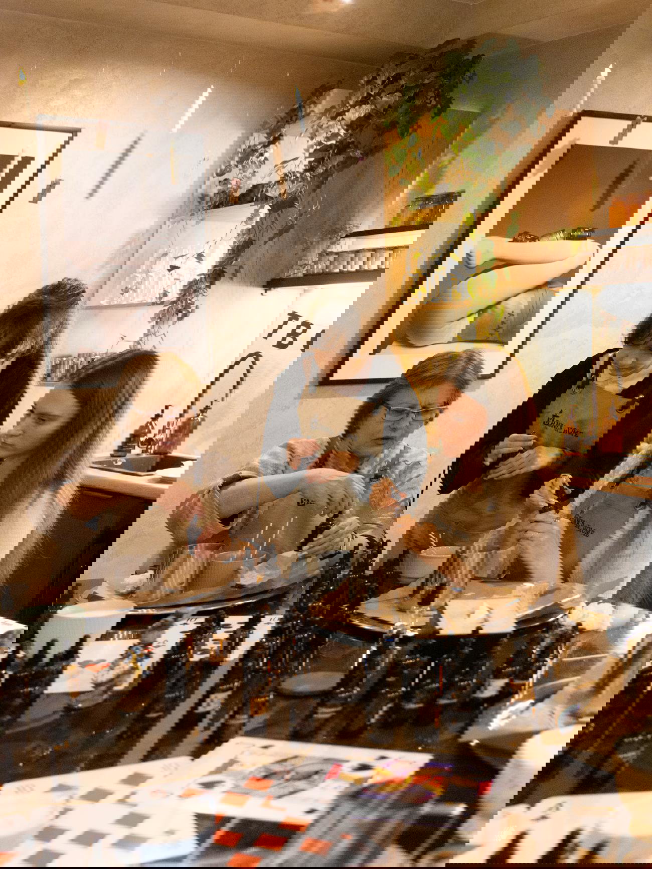 Участники мастер-класса Banka Home в фартуках смешивают ароматы и готовят материалы — стол заполнен коричневыми флаконами и инструментами.