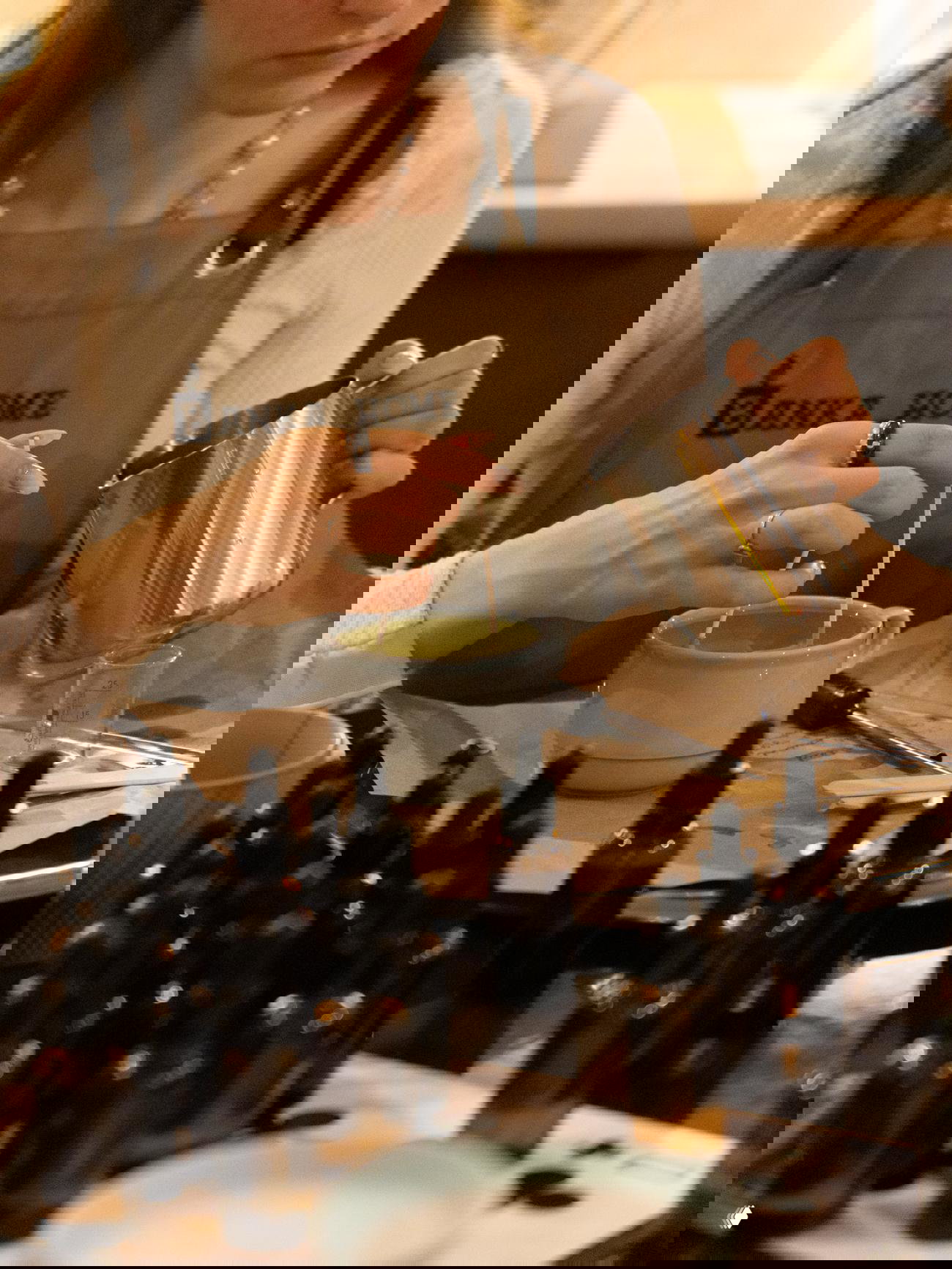 Крупный план рук участницы, заливающей расплавленную основу в форму и держащей мерный кувшин — рабочий процесс изготовления свечи в Banka Home.