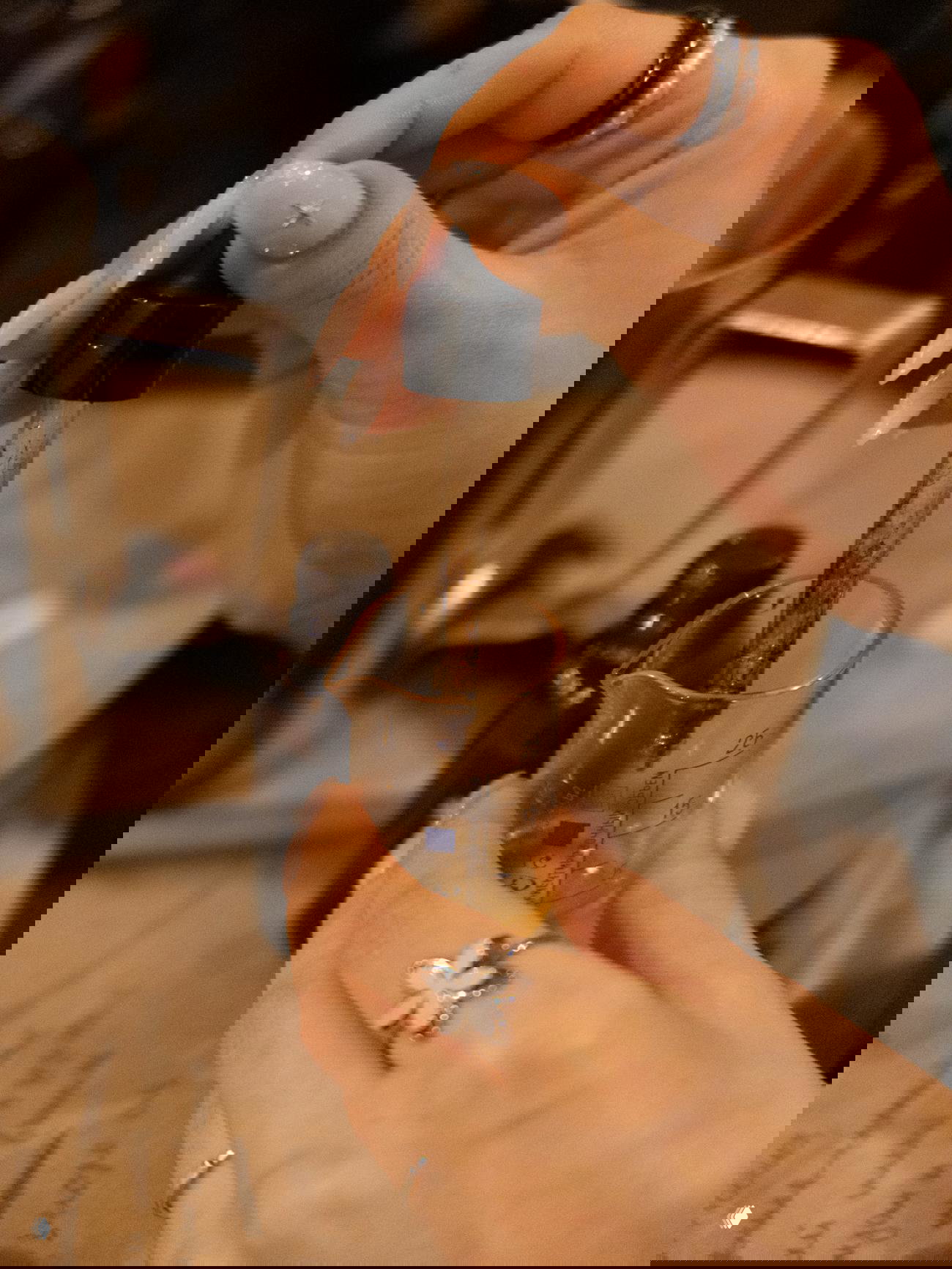 Руки с пипеткой добавляют ароматические капли в мензурку на фоне множества янтарных флаконов — подготовка ароматической композиции для свечи.