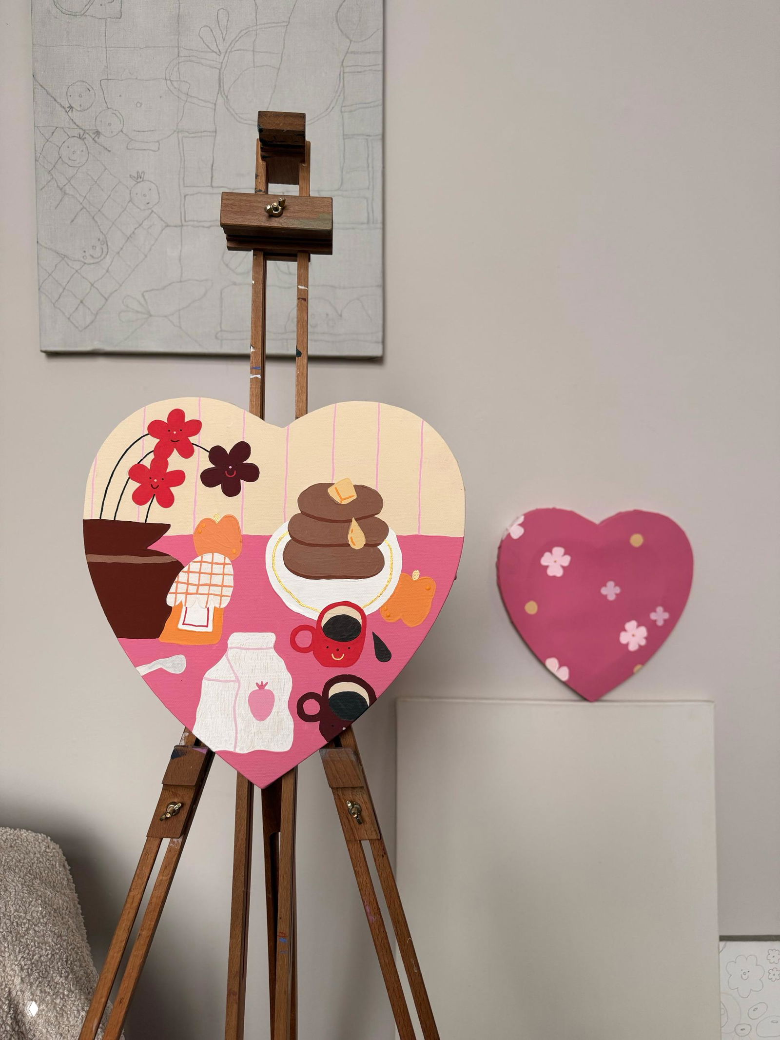 Сердце‑панно с яркой иллюстрацией завтрака на мольберте в студии — декоративная картина в форме сердца, часть выставочного декора для 14 февраля.