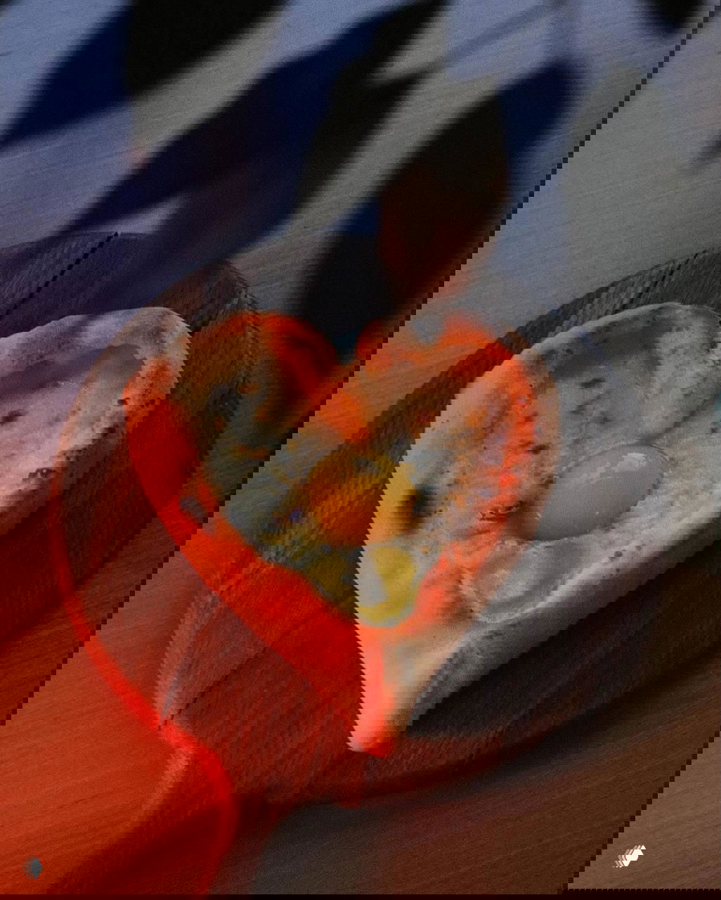 Хлеб или хачапури в форме сердца с целым яйцом в центре, поданный на деревянной доске — тёплая романтичная подача в рамках спешлов рынка.