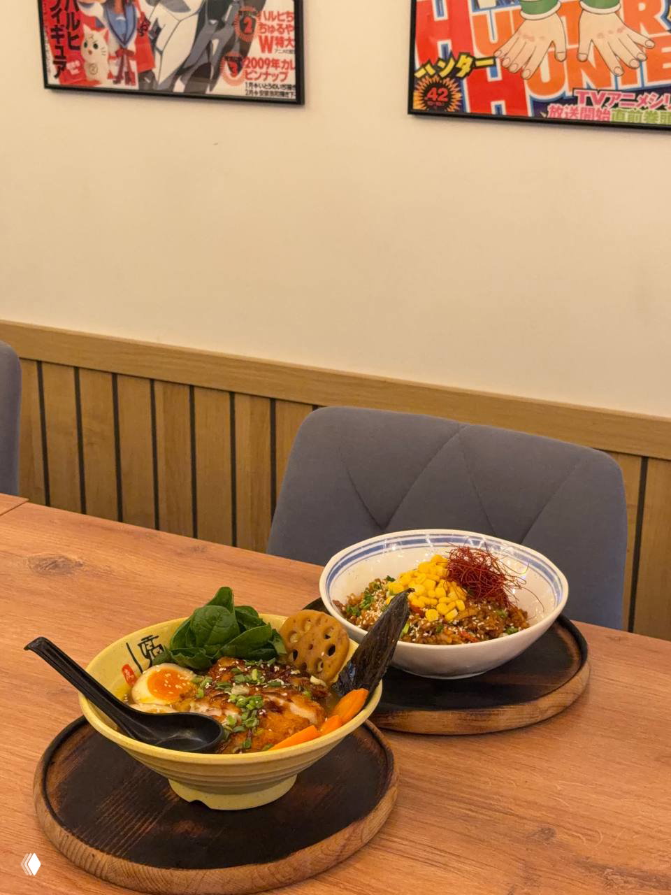 На столе две порции: карри рамэн с курицей кацу и вок на рисе с фаршем, подача на деревянных подставках, вид со стороны столика.