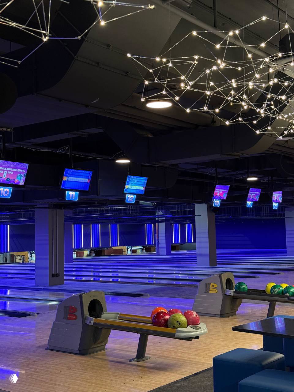 Большой зал боулинга MazaPark с синей подсветкой: дорожки, табло и разноцветные шары на стойках в просторном помещении.