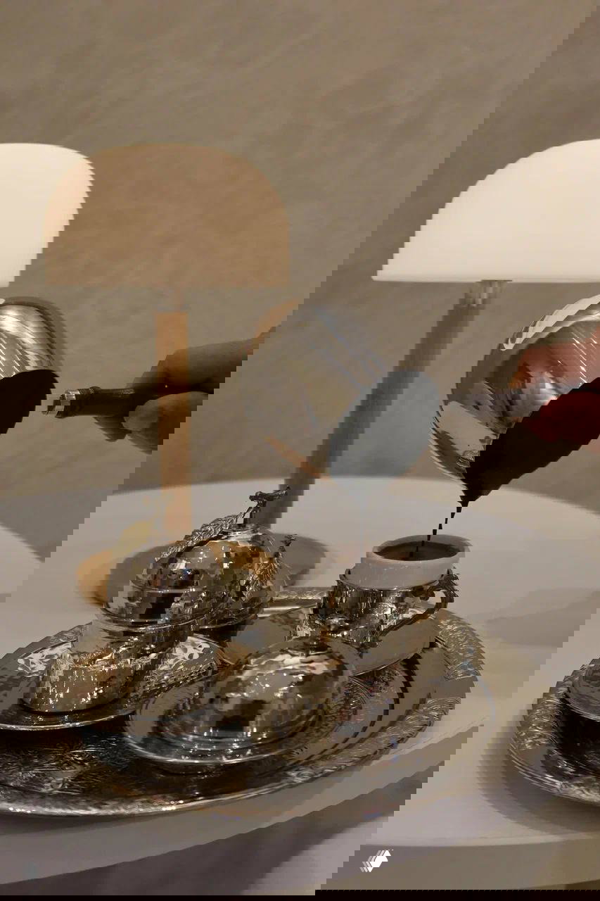 Наливание крепкого турецкого кофе в небольшую чашку на украшенном серебряном подносе — традиционная подача с металлической посудой и крышками.