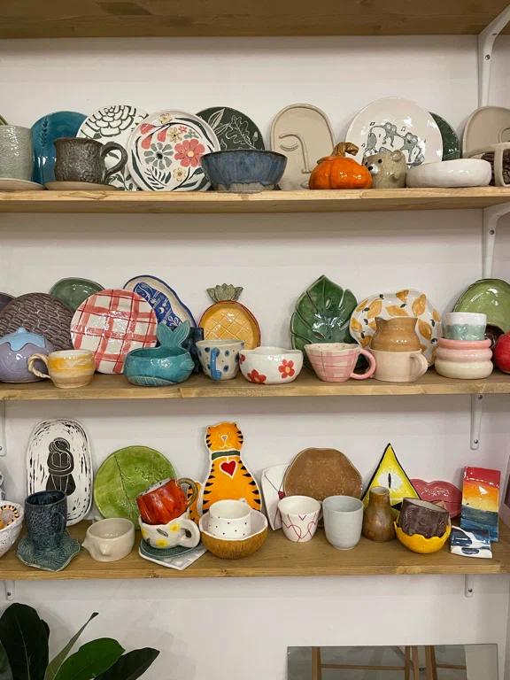 Полка с множеством небольших расписных керамических изделий — примеры работ учеников и сувениров из студии.