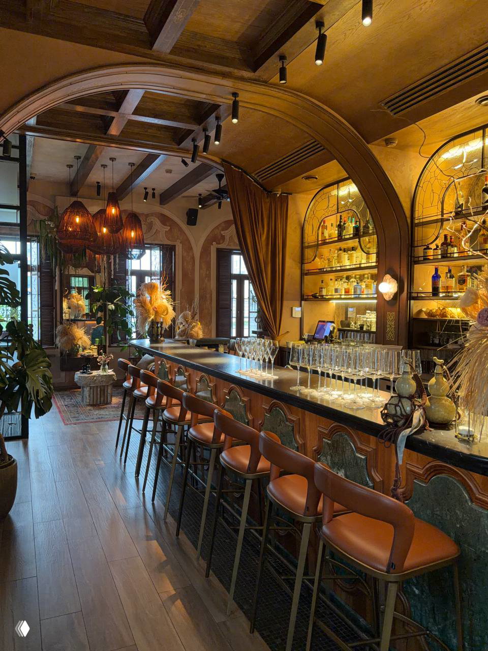 Барная зона Garden Bistro Villa Madelina: длинная мраморная стойка, высокие стулья, деревянные арки и тёплое освещение.