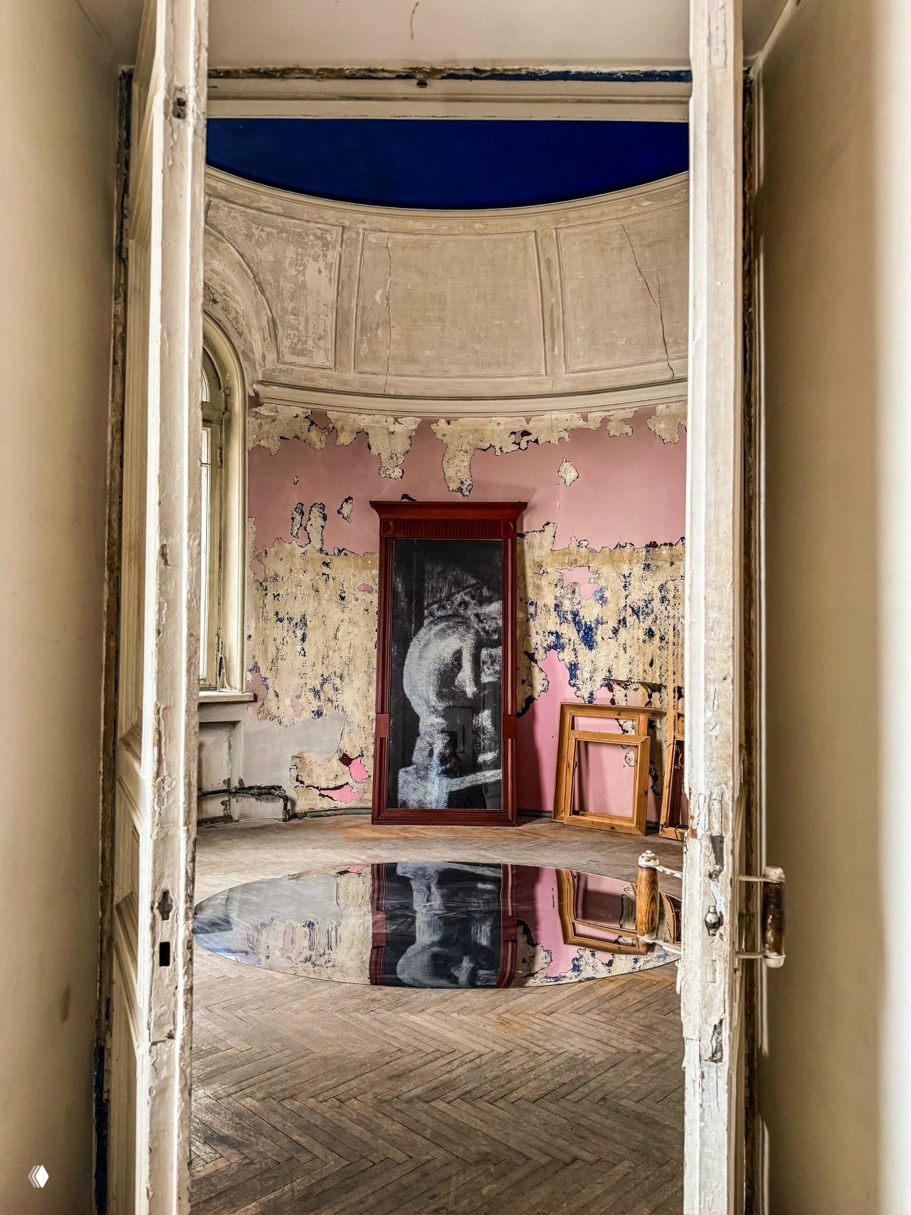 Ротонда с облупившейся лепниной и розовой стеной, в помещении — зеркало в раме и круглая отражающая инсталляция на полу, часть экспозиции в квартире.