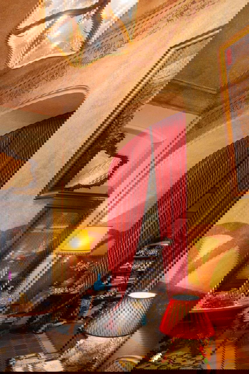 Интерьер в старом стиле: антикварная мебель, красные портьеры и лампы, витрина с предметами и декоративная роспись на стенах в комнатах мастерской.