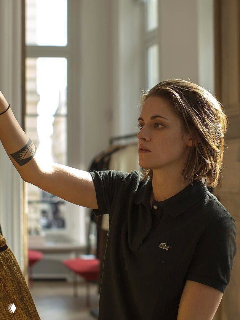 Повседневный кадр молодой женщины с короткой стрижкой и татуировкой на предплечье в светлом помещении — рабочая атмосфера закулисья.