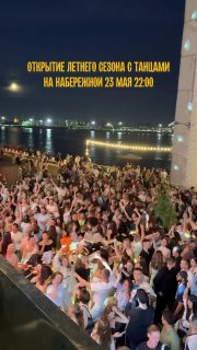 Толпа людей на ночной набережной у бара SimpleWine: танцы, огни города и публика с телефонами во время открытия летнего сезона.