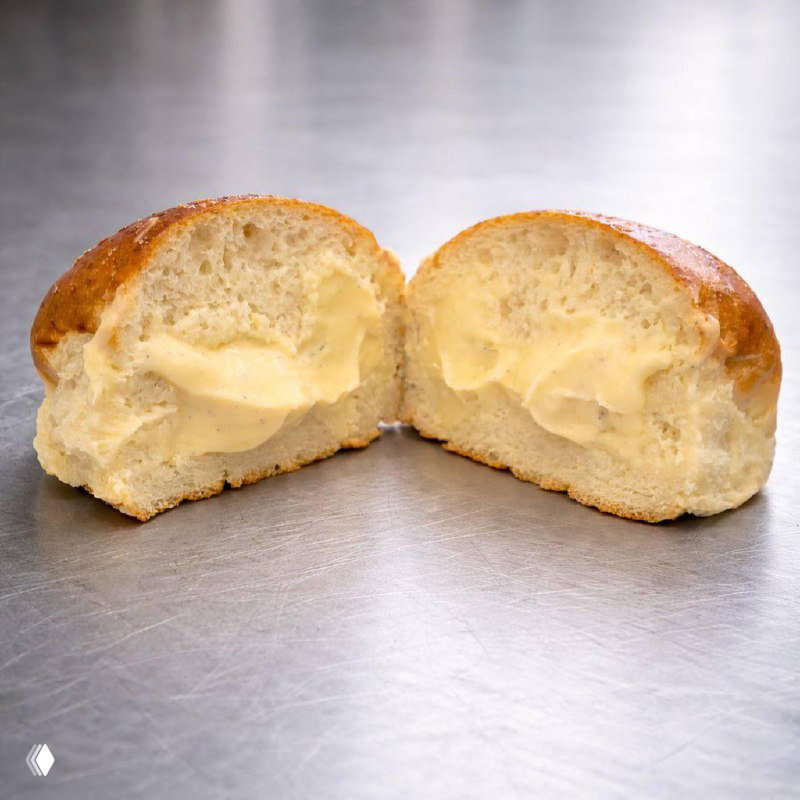 Разрезанный сливочный бриош с крем патисьер на металлической поверхности — крупный план текстуры теста и кремовой начинки.