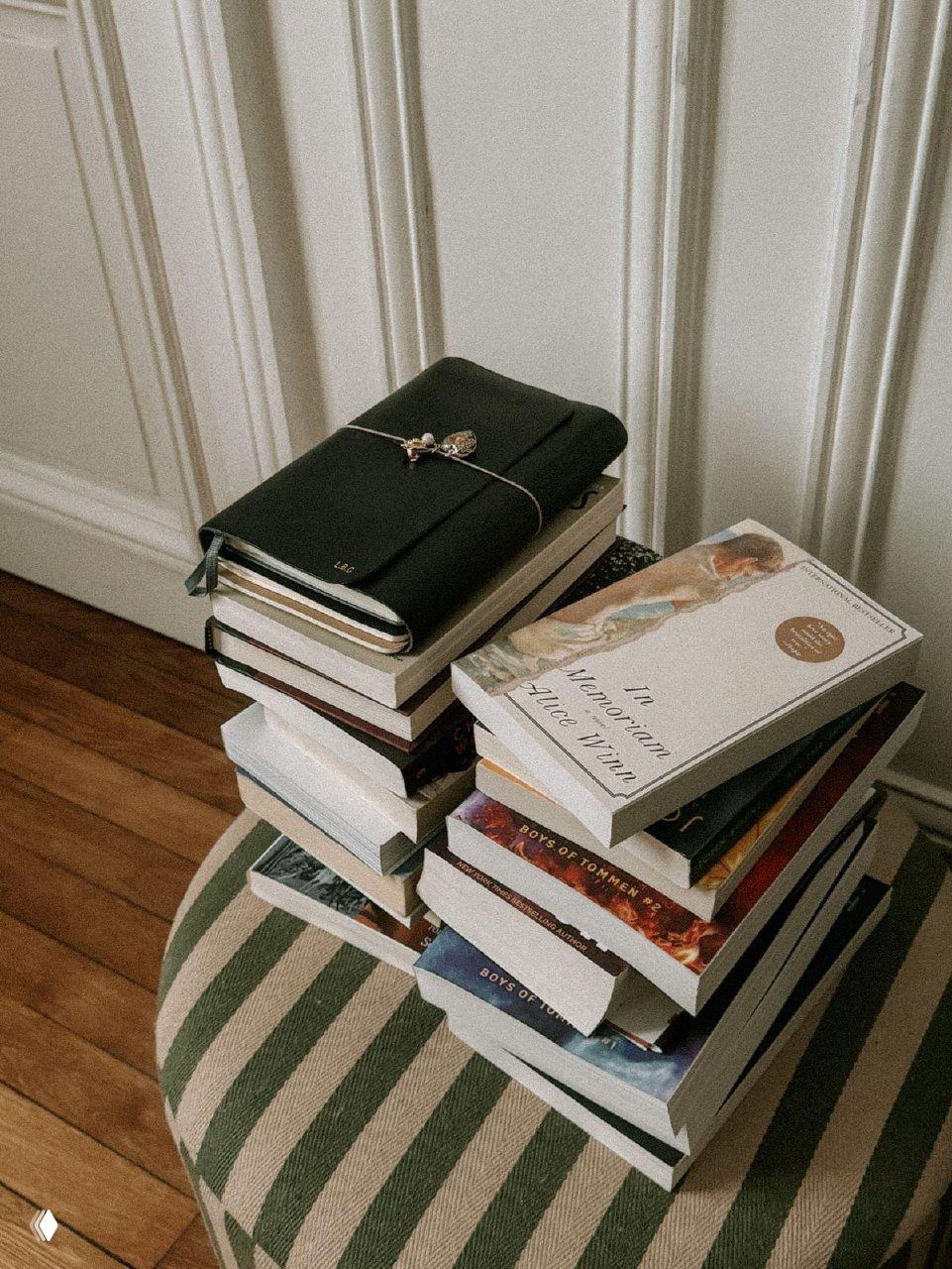 Стопка книг и блокнот на полосатом пуфе: фотография книг, которые можно принести или найти на книжной барахолке, тёплая интерьерная композиция.