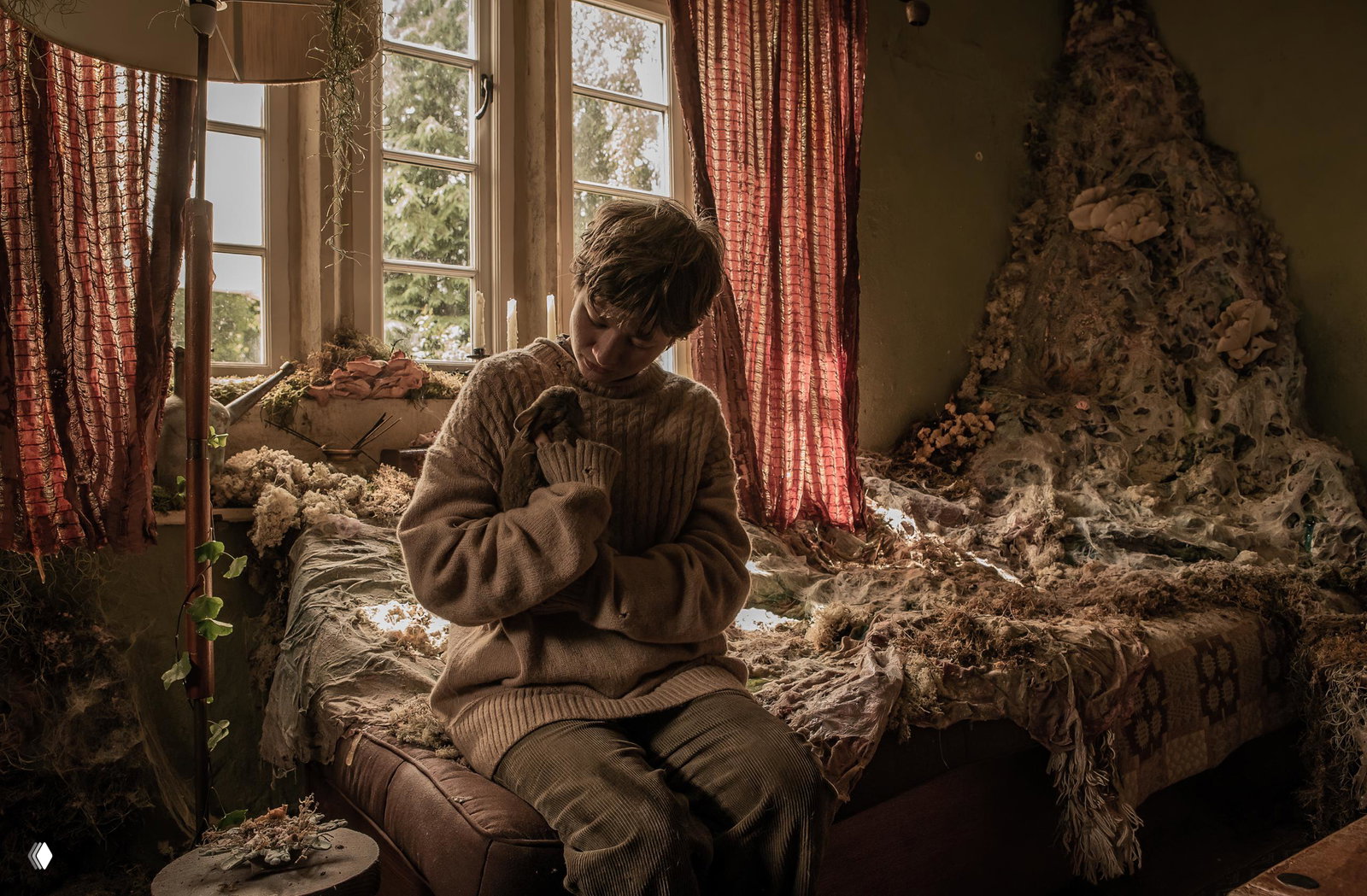 Интерьерная сцена: ребёнок в тёплом свитере держит кролика на руках в запущенной комнате с паутиной, мхом и мягким дневным светом из окна — уют и мрачность одновременно.