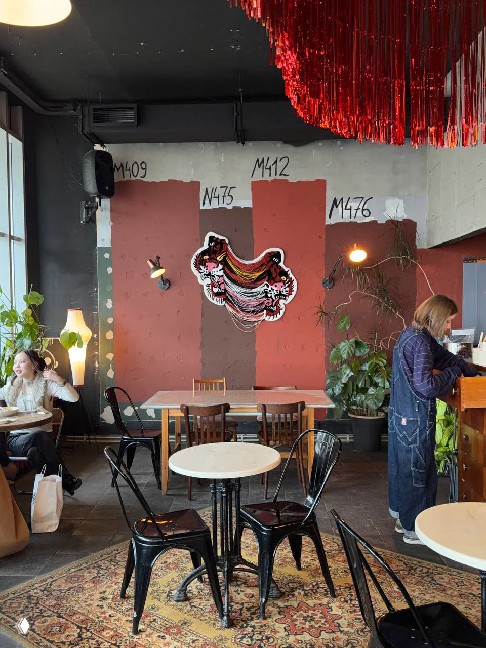 Зона посадки в OSSU: столы на коврах, граффити на стене и зеленые растения, сочетание индустриального и уютного стиля для гостей