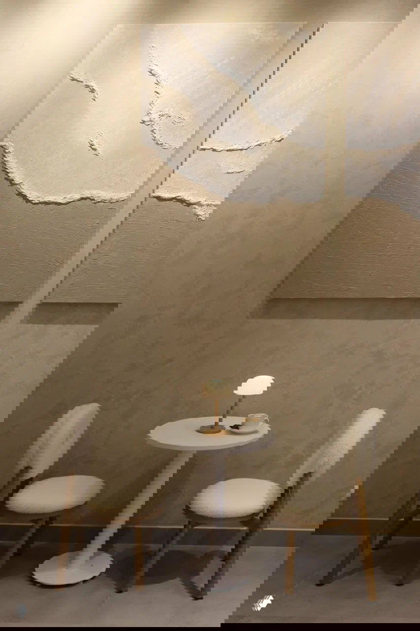 Минималистичный уголок: два мягких кресла, маленький круглый стол и абстрактные бежевые картины на стене — спокойная атмосфера в Nerede.