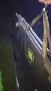 Размытое ночное фото оборудования для взвешивания и транспортировки рыбы на берегу — чехол или весы, частично видно освещение.