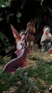 Фотография рождественского вертепа: картонные фигурки ангелов и святых на соломенной подстилке между еловыми ветвями