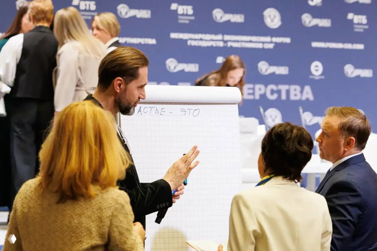 Небольшая рабочая группа у флипчарта во время сессии: обсуждение идей, заметки на бумаге и активная коммуникация между участниками.