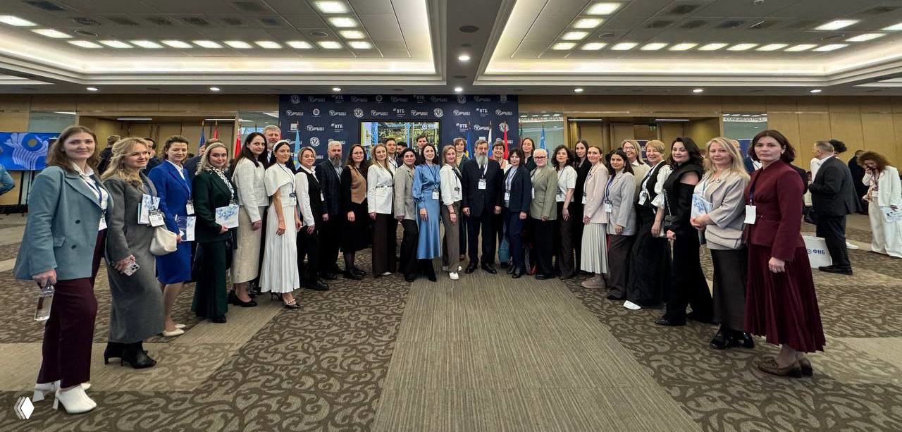 Широкая групповая фотография участников представительной делегации форума в фойе конферец-зала, демонстрация масштаба и географии команды.