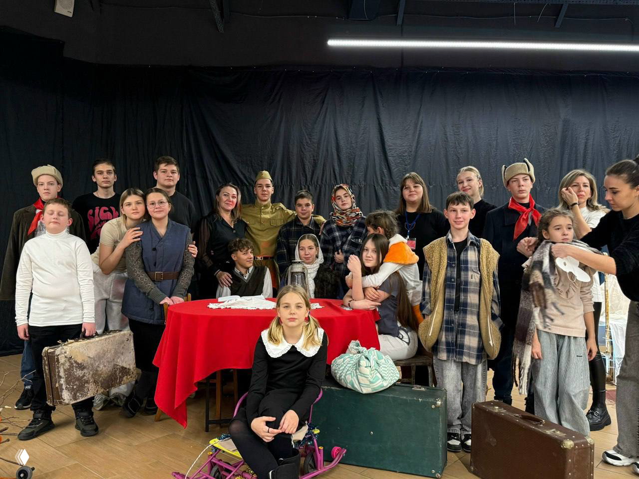 Групповая фотография участников спектакля и детей на сцене в костюмах и с реквизитом — команда постановки после представления.