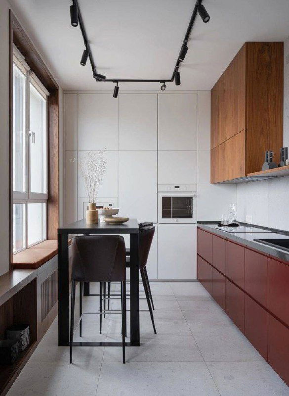 Кухонная зона и стол с предметами сервировки, кадр частично искажен цифровыми артефактами; видна планировка островной рабочей поверхности и проход в гостиную.